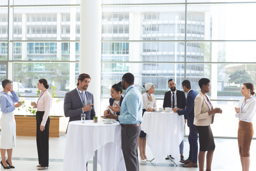 Front view of diverse business people interacting with each other at table after a conference in office lobby Front view of diverse business people interacting with each other at table after a conference in office lobby